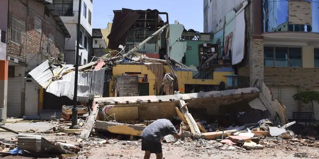 A man takes a photo of a building that collapsed after an earthquake shook Machala, Ecuador, Saturday, March 18, 2023.