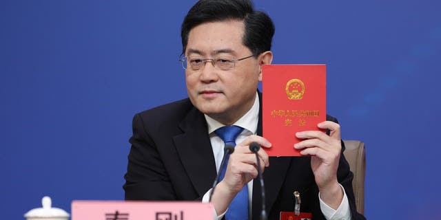 China's foreign minister Qin Gang holds a China's constitution during a press conference at Media Center.
