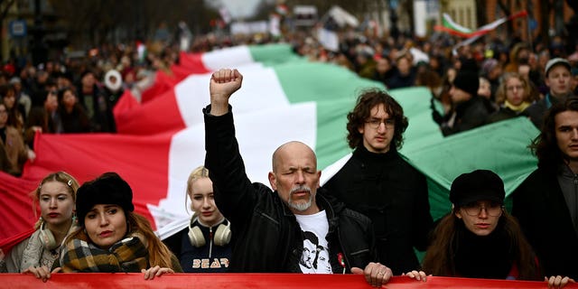 People carry a huge Hungarian flag during a march while calling for educational reforms in Budapest, Hungary, on March 15, 2023.