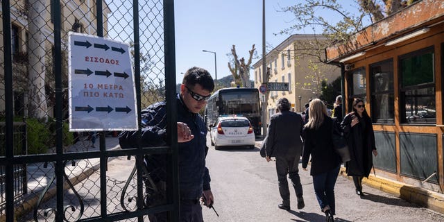 A Greek police officer closes the entrance of the courthouse following the transfer of suspects that have been charged with membership in a terrorist organization, in Athens, on March 2023.