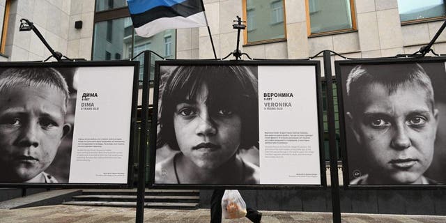 A pedestrian walks past the "Children of Donbass" open-air photo exhibition outside the Estonian Consulate in Moscow Jan. 23, 2023.
