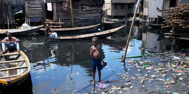 A child stands in filthy water surrounded by garbage in Nigeria's economic capital Lagos, on March. 20, 2023. March 22 is World Water Day, established by the United Nations and marked annually since 1993 to raise awareness about access to clean water and sanitation. Many children in Africa lack access to clean drinking water.