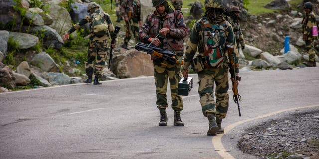 Indian Border Security Force soldiers patrol a highway as Indian army convoy passes through on a highway leading toward Leh, bordering China, on June 19, 2020 in Gagangir, India. 