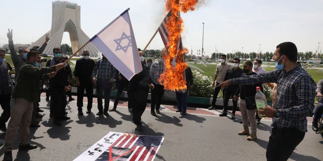 Demonstrators burn representations of Israeli and U.S flags during the annual Al-Quds, or Jerusalem Day rally, with the Azadi (Freedom) monument tower seen at left, in Tehran, Iran, Friday, May 7, 2021. Iran held a limited anti-Israeli rally amid the coronavirus pandemic to mark the Quds Day. After the late Ayatollah Khomeini, leader of the Islamic Revolution and founder of present-day Iran, toppled the pro-Western Shah in 1979, he declared the last Friday of the Muslim holy month of Ramadan as an international day of struggle against Israel and for the liberation of Jerusalem.