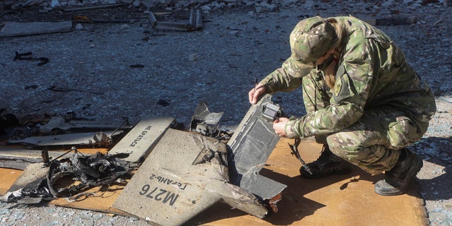 A police officer inspects parts of an unmanned aerial vehicle (UAV), what Ukrainian authorities consider to be an Iranian made suicide drone Shahed-136, at a site of a Russian strike on fuel storage facilities, amid Russia's attack on Ukraine, in Kharkiv, Ukraine October 6, 2022. 