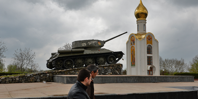 People pass next to a Soviet-era tank, now a monument celebrating the victory of the Red Army against fascist Germany, in Tiraspol, the main city of Trans-Dniester separatist region of Moldova, in April 2014.