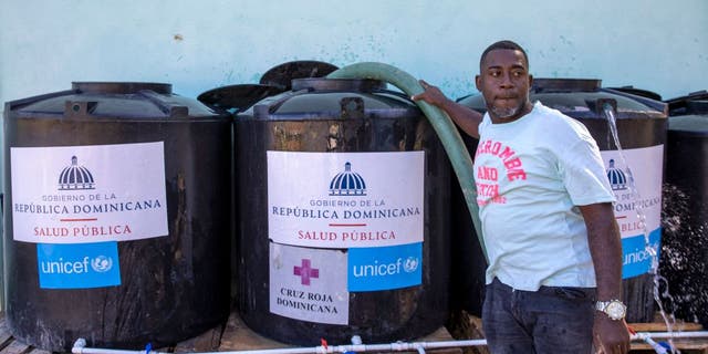 A worker from the state drinking water company refills containers installed by the Public Health Ministry due to a cholera outbreak in Santo Domingo, on Feb. 9, 2023.