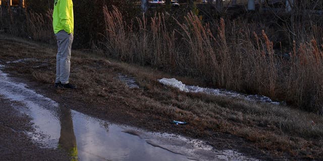 A contractor working for the city of Jackson, Mississippi, watches as water from a damaged main runs along McLaurin Road on Dec. 29, 2022.