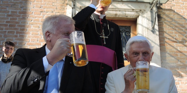The retired Pope Benedict XVI and the premier of the state of Bavaria, Horst Seehofer, drink a glass of beer in the Vatican Garden in Vatican City. Benedict's private secretary Georg Gaenswein stands behind the two. 