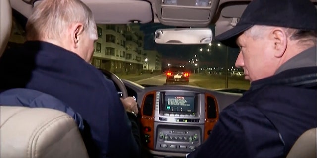 Russian President Vladimir Putin, left, and Russian Deputy Prime Minister Marat Khusnullin drive a car during their visit to Mariupol. Putin traveled to Crimea to mark the ninth anniversary of the Black Sea peninsula's annexation from Ukraine.