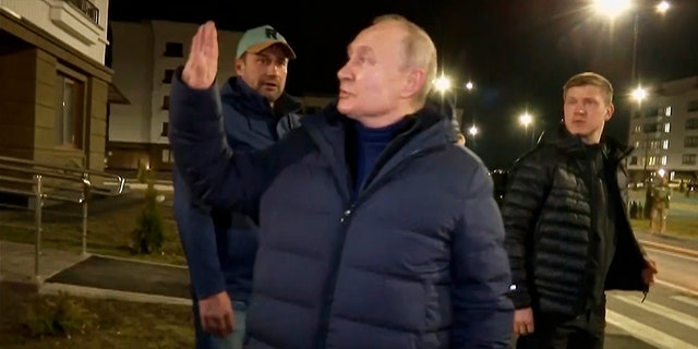 Russian President Vladimir Putin waves to local residents after visiting their new flat during his visit to Mariupol in the Russian-controlled Donetsk region of Ukraine.