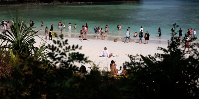 Tourists enjoy the beach during an hour-long visit, where swimming is forbidden and people are only allowed to enter water up to their knees, in Maya Bay at the Phi Phi Island National Park, in Phi Phi Leh Island, Krabi province, Thailand, Feb. 24, 2023. On any given day in Maya Bay, up to 40 blacktip reef sharks cruise in the cyan shallows while about 4,000 tourists visit its white-sand beach flanked by towering cliffs.