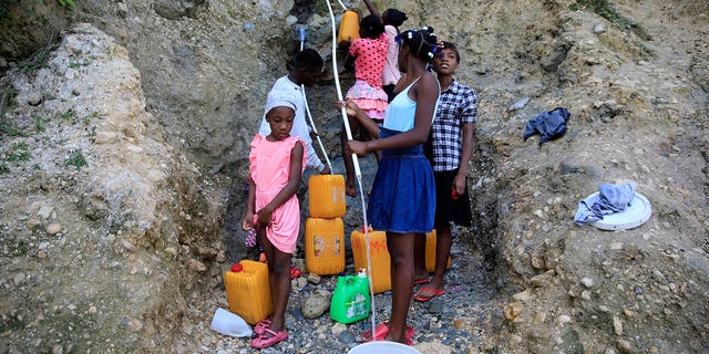 People, without running water at home, collect water from a ravine in Port-au-Prince, Haiti, on March 21, 2023. 