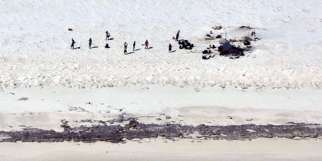 Fishermen from Indonesia stand on a beach on Bedwell Island, Australia, on April 17, 2023. At least eight Indonesian fishermen are feared dead and another 11 have been rescued.