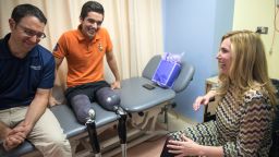 In this Monday, Feb. 13, 2017 photo, Heather Abbott, right, prosthetist David Rotter, left, and Vidal Lopez talk amongst themselves at the University of Illinois at Chicago Hospital, in the Near West Side neighborhood. Abbott, a survivor of the Boston Marathon bombing and founder of The Heather Abbott Foundation, teamed up with Scheck & Siress, a Chicago based prosthetic firm, to provide Lopez with new customizable prosthetic legs. Vidal was born in Chicago but grew up in Mexico. A car crash involving a tractor trailer in July 2016, left him without his legs. He wrote to the Heather Abbott Foundation with hopes to receive a grant to help him pay for the prosthetic legs that he needed. Heather was touched by his story and decided to provide Vidal with the financial support he needed to secure his future. (Alyssa Pointer/Chicago Tribune via AP)