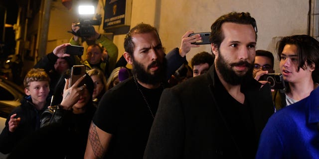 Young fans and media surround Andrew Tate, left, and his brother Tristan as they leave a police detention facility in Bucharest, Romania, after his release from prison on Friday March 31, 2023. An official on Friday said Tate, the divisive internet personality who has spent months in a Romanian jail on suspicion of organized crime and human trafficking, has won an appeal to replace his detention with house arrest. (AP Photo/Alexandru Dobre)