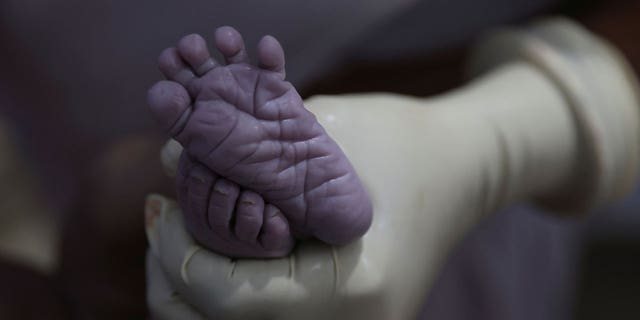 A nurse holds the feet of a newborn baby in Bihar, India, on March 21, 2023. India is about to become the most populous country in the world. 