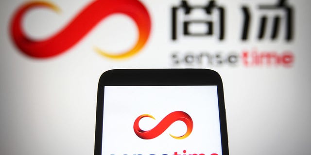 In this photo illustration, SenseTime logo is seen displayed on a smartphone and a PC screen. 