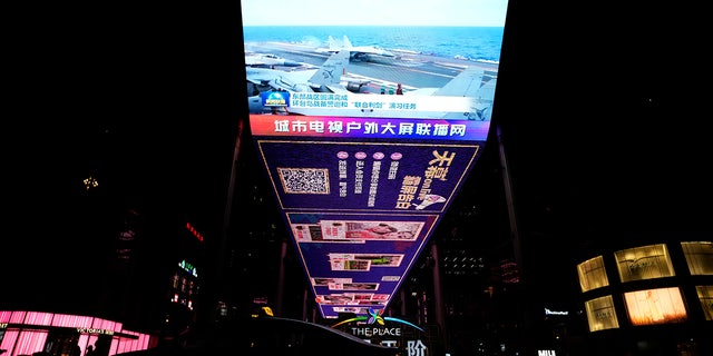The evening news broadcast shows Chinese fighter jets on an aircraft carrier with the Chinese subtitles "Eastern Battle District successfully concludes the patrol exercise around the Taiwan island and Joint Sword exercise" on an outdoor screen in Beijing, on Monday, April 10.