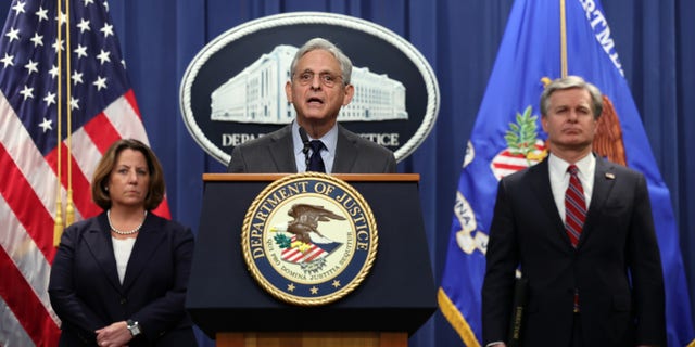 US Attorney General Merrick Garland speaks at podium alongside Deputy Attorney General Lisa Monaco and FBI Director Christopher Wray