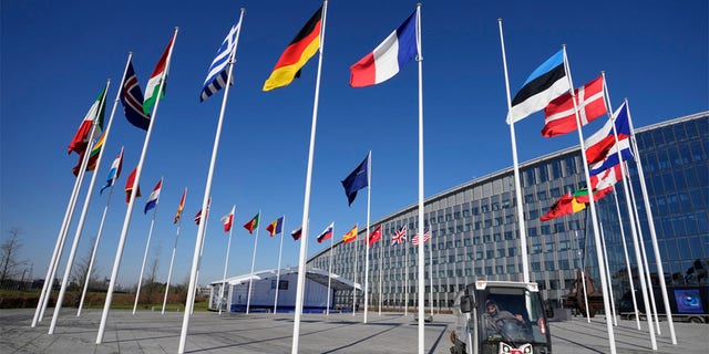 An empty flagpole stands between the national flags of France and Estonia outside NATO headquarters in Brussels, Monday, April 3, 2023. 