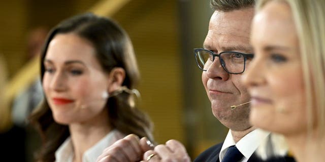 Chair of SDP Sanna Marin, left, and chair of The Finns party Riikka Purra, right, look on as National Coalition Party chair Petteri Orpo cheers at the Finnish parliamentary elections media reception at the Finnish Parliament in Helsinki, Finland on Sunday, April 2, 2023. 