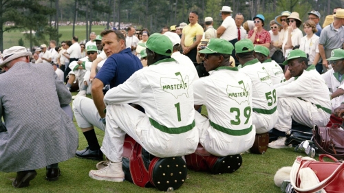Palmer looks over his shoulder as he sits with a group of caddies during the 1965 Masters.