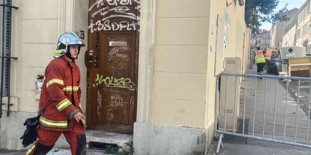 A firefighter walks near the scene where a building collapsed, in Marseille, southern France, on April 10, 2023.