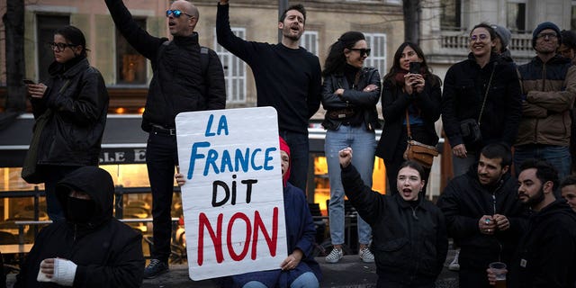 A woman holds a sign reading "France says no" during a demonstration in Marseille, southern France, on March 16, 2023. French protestors are opposing the government’s proposal to raise the retirement age from 62 to 64.