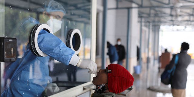 A healthcare worker collects a test swab sample from a child at a testing center inside a hospital in New Delhi, India, on Jan. 14, 2022. India is seeing an uptick in daily COVID-19 cases.