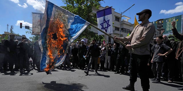 Iranian demonstrators burn a representation of the Israeli flag in their rally to mark Jerusalem Day, an annual show of support for the Palestinians, in Tehran, Iran, on April 14, 2023.