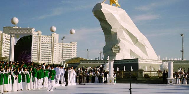 People gather for the monument unveiling ceremony in Ashgabat, Turkmenistan Monday, May 25, 2015. The isolated energy-rich Central Asian nation of Turkmenistan has unveiled a gold-leafed statue of the president in a gesture intended to burnish the leaders burgeoning cult of personality. The 21-meter monument presented to the public Monday consists of a statue of President Gurbanguly Berdymukhamedov atop a horse mounted on a towering pile of marble. (AP Photo/Alexander Vershinin)