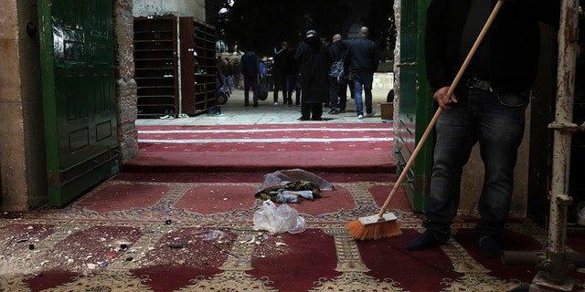A Palestinian worshipper sweeps debris after a raid by Israeli police at the Al-Aqsa Mosque compound in the Old City of Jerusalem, Wednesday, April 5, 2023. 