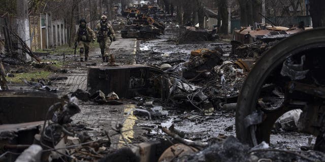 Soldiers walk amid destroyed Russian tanks in Bucha, on the outskirts of Kyiv, Ukraine, Sunday, April 3, 2022.