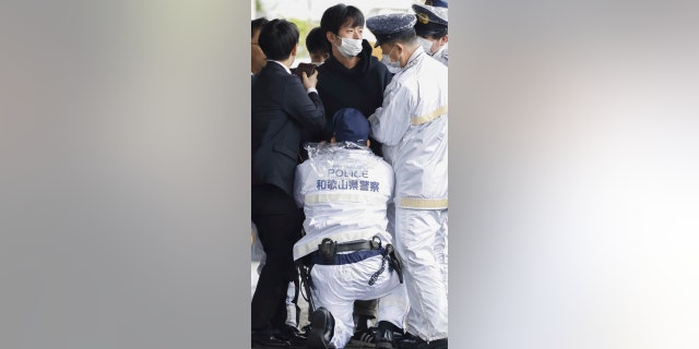 A man, center, is caught after what appeared to be a smoke bomb was thrown at a port in Wakayama, western Japan, Saturday, April 15, 2023. 