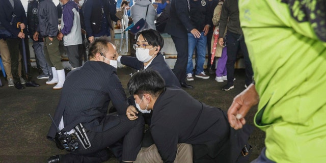 A man, on the ground, who threw what appeared to be a smoke bomb, is caught at a port in Wakayama, western Japan Saturday, April 15, 2023. 
