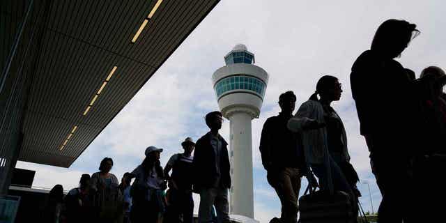 Travelers wait in long lines outside the terminal building to check in and board flights at Amsterdam's Schiphol Airport, Netherlands, on June 21, 2022. A judge ruled on April 5, 2023, that the Dutch government cannot order the Schiphol Airport to reduce the number of flights.