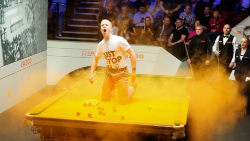 A Just Stop Oil protester jumps on the table and throws orange powder paint during a match.