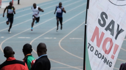 Athletes run as an anti doping banner is seen during the Kenya National Trials at Kasarani Stadium in Nairobi on June 21, 2018.