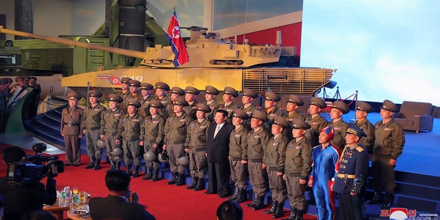 North Korean leader Kim Jong Un, center, poses for a group photo with fighter pilots who made the demonstration flight at the opening of an exhibition of weapons systems in Pyongyang, North Korea.