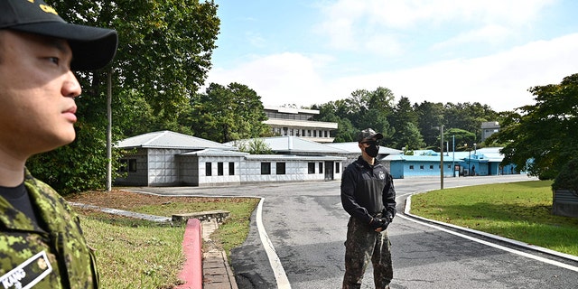A United Nations Command soldier, left, and a South Korean soldier, right, stand near North Korea's Panmon Hall at Panmunjom, in the Joint Security Area of the Demilitarized Zone on Oct. 4, 2022.