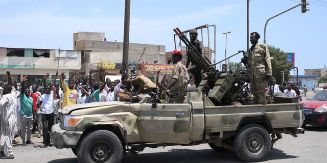 Sudanese greet army soldiers, loyal to army chief Abdel Fattah al-Burhan, in the Red Sea city of Port Sudan on April 16, 2023. Battling fighters in Sudan said they had agreed to an hours-long humanitarian pause, including to evacuate wounded, on the second day of raging urban battles that killed more than 50 civilians including three U.N. staff and sparking international outcry.