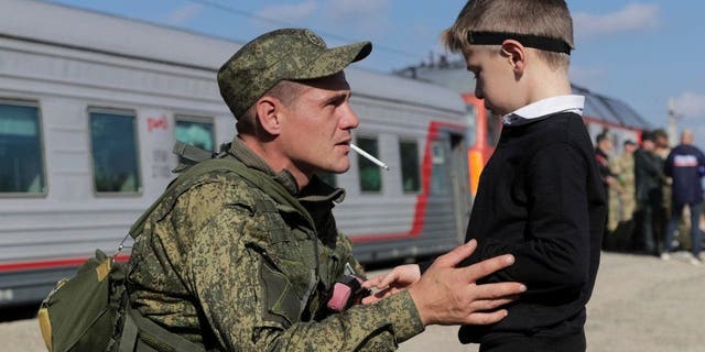 A Russian recruit speaks to his son at a railway station in Prudboi, Volgograd region of Russia, Sept. 29, 2022.