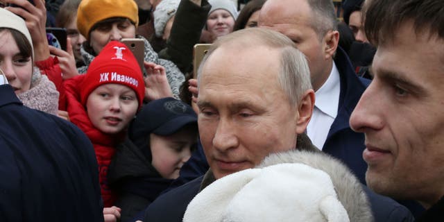 Russian President Vladimir Putin hugs a crying baby as he greets residents in Ivanovo, Russia, on March 6, 2020. (Mikhail Svetlov / Getty Images)