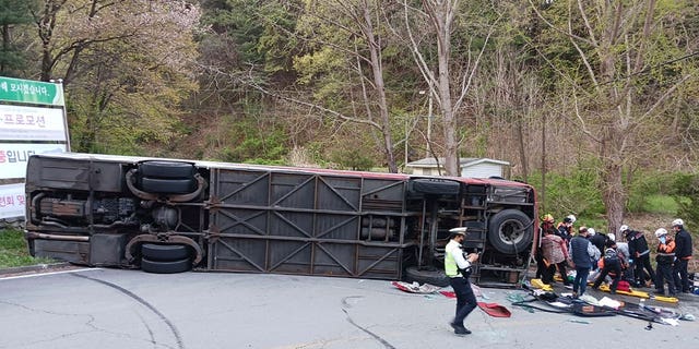 Emergency personnel rescue tourists after a bus fell on a road in Chungju, South Korea, on April 13, 2023. A 62-year-old woman died in the incident.