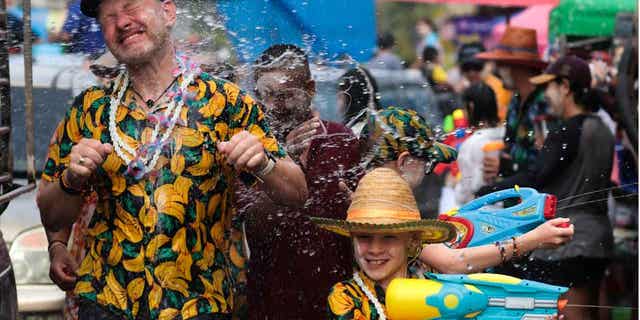 A man sprays water at a tourist to celebrate the Songkran festival in Prachinburi Province, Thailand.