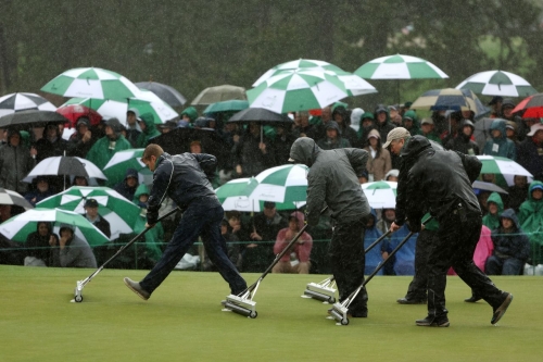 Groundskeepers remove standing water on green during the continuation of the weather-delayed second round on Saturday. 