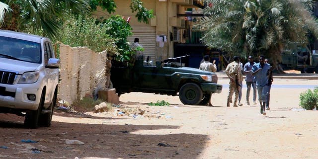 People walk past a military vehicle in Khartoum on April 15, 2023, amid reported clashes in the city.
