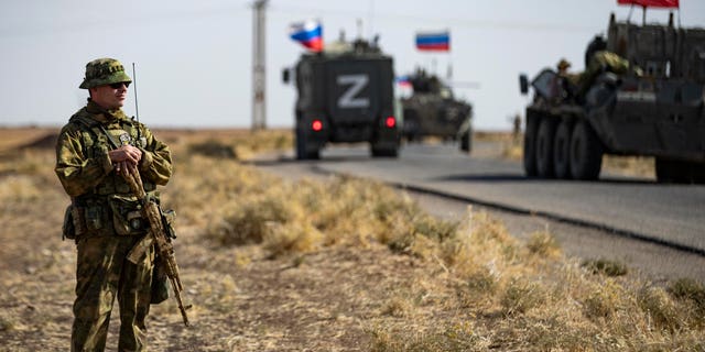 Soldiers of a Russian military convoy and their U.S. counterparts exchange greetings as their patrol routes intersect in an oil field near Syria's al-Qahtaniyah town in the northeastern Hasakah province, close to the border with Turkey, on October 8, 2022. 