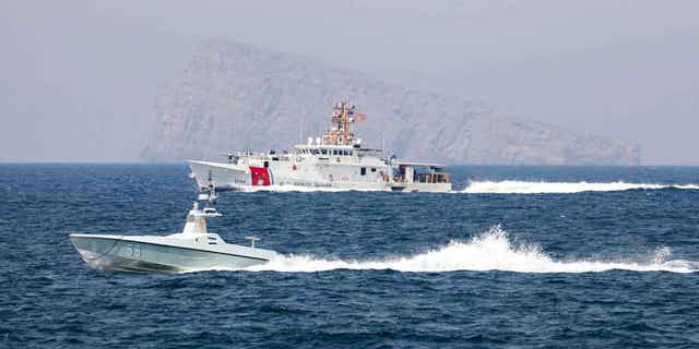 A U.S. Navy drone boat and the U.S. Coast Guard transit the Strait of Hormuz on April 19, 2023.